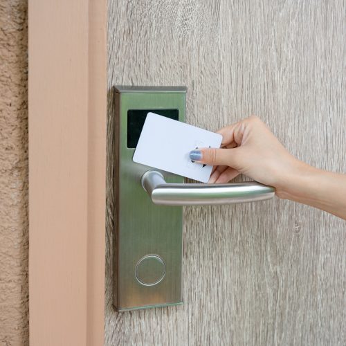 Hand holding key card scanning to unlock wooden door at resort