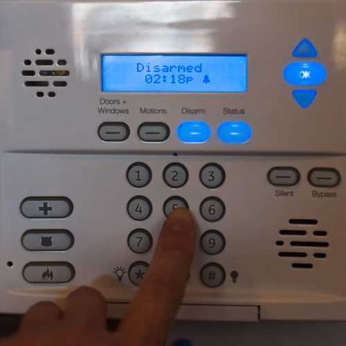 Woman’s finger entering passcode into security alarm system on a wall at a restaurant